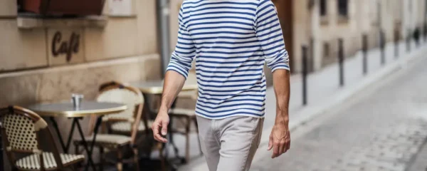 Homme trentenaire portant une marinière rayée bleu et blanc dans une rue française